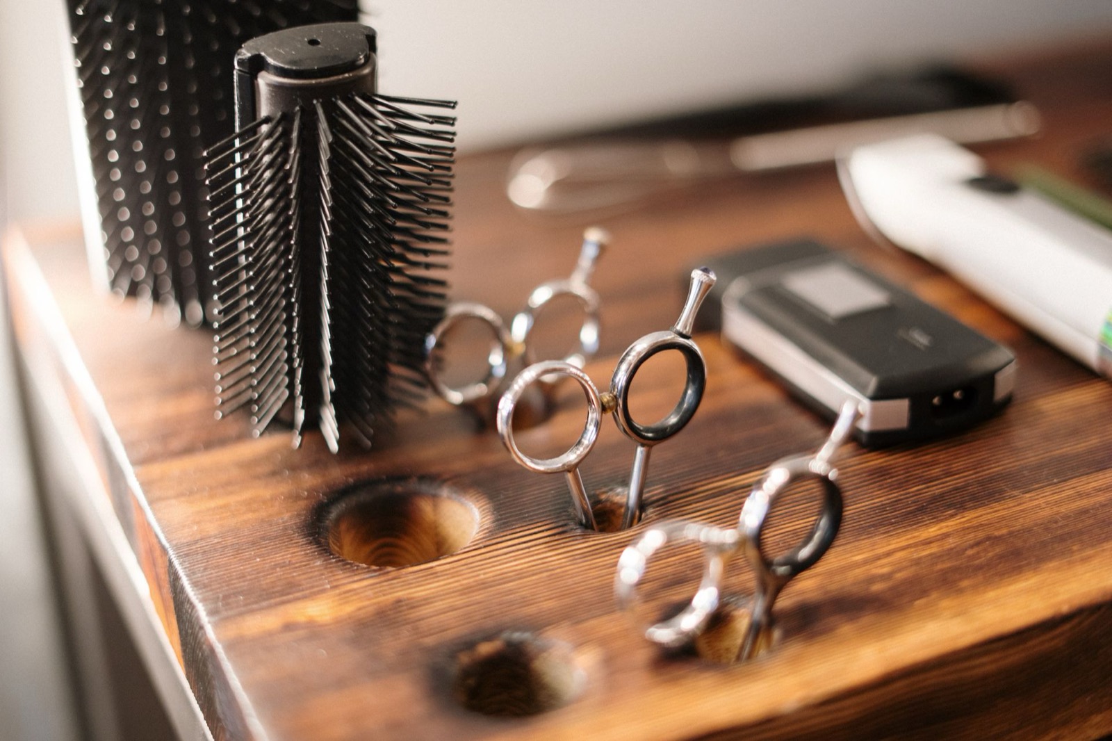 Détail des outils de coiffure : ciseaux et brosse posés sur un plan en bois