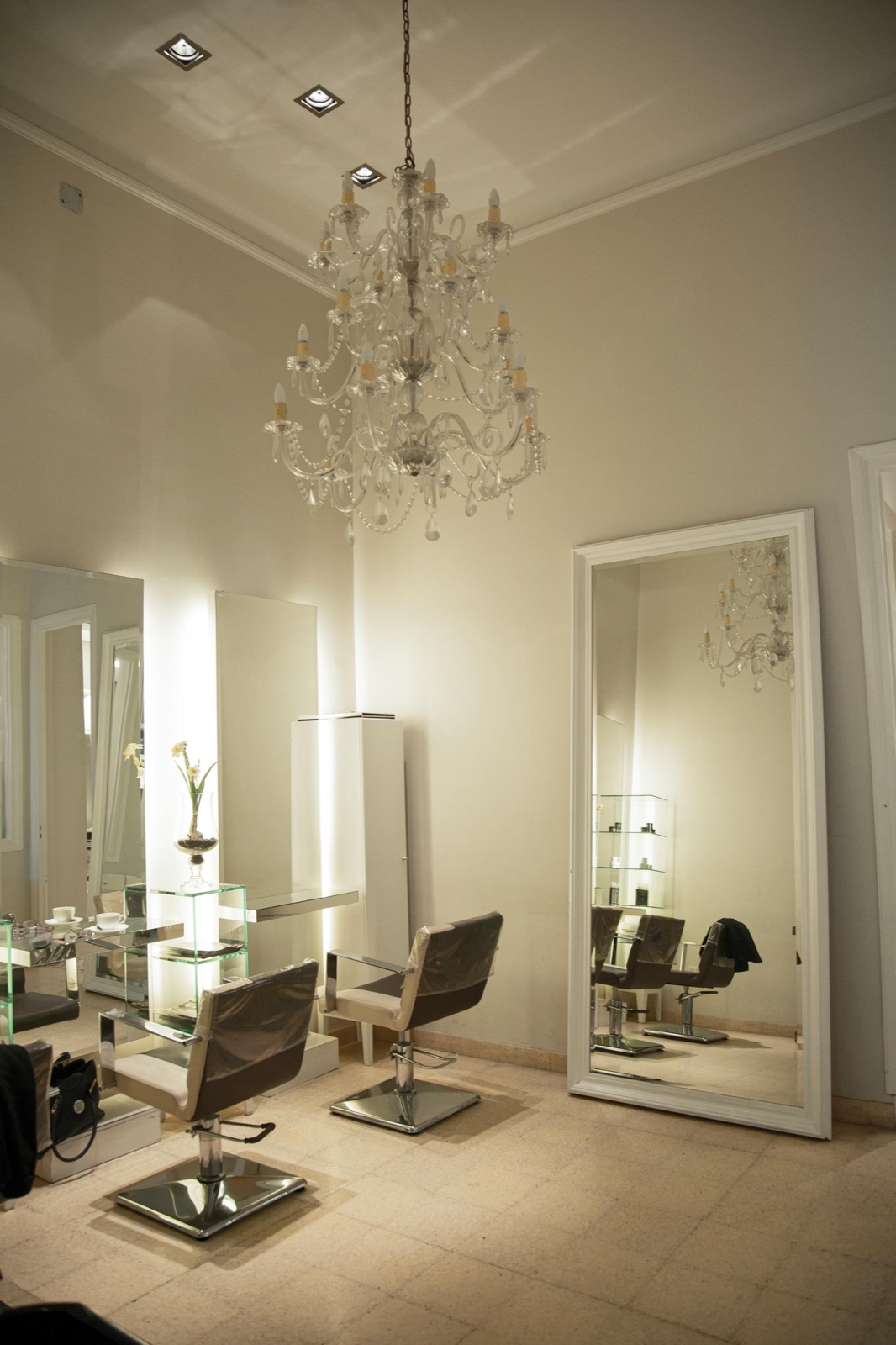 Intérieur du salon Beauty'Zen à Menton : fauteuils de coiffage, grand miroir et lustre dans une ambiance claire et chaleureuse