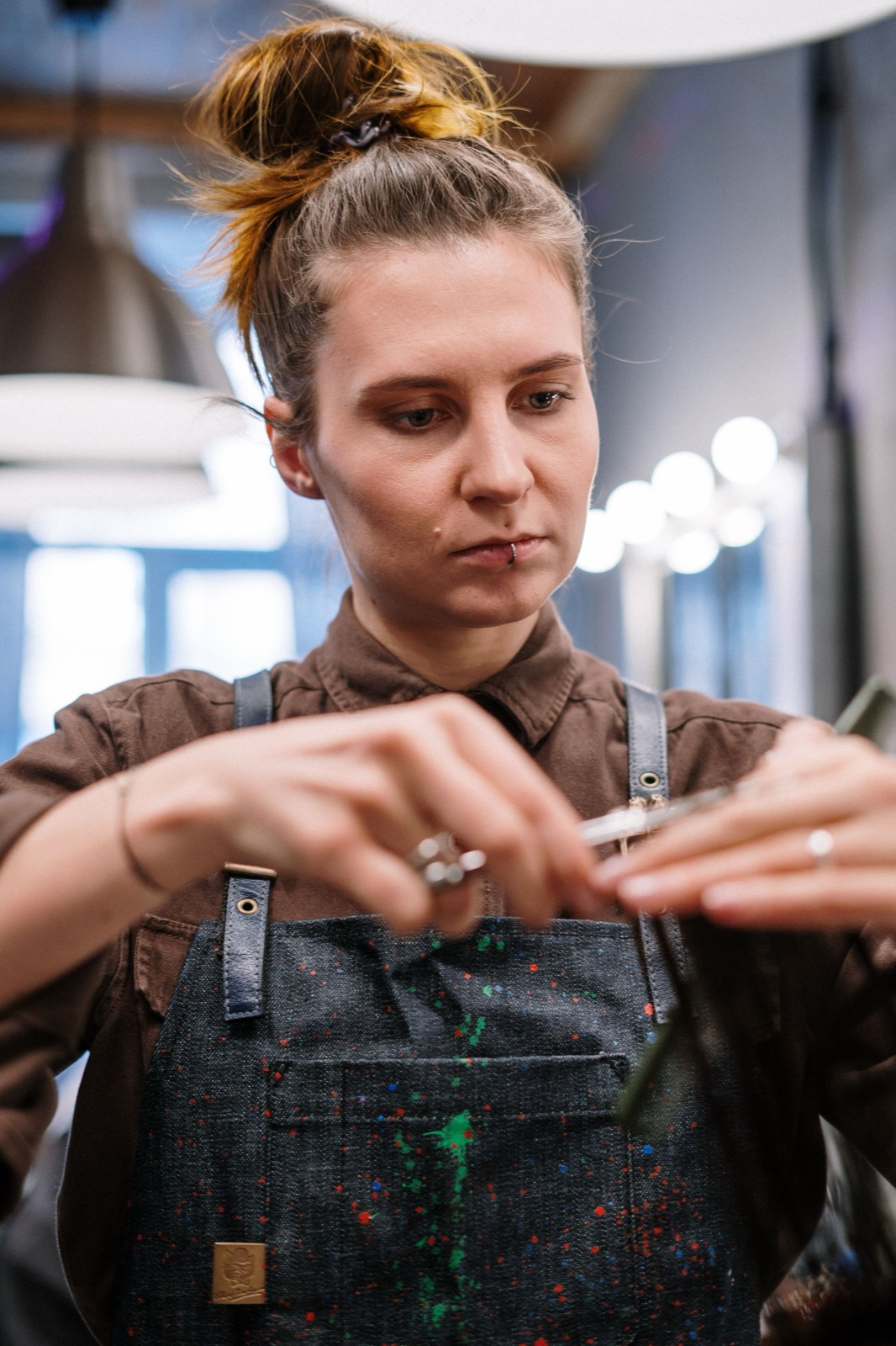 Styliste de Beauty'Zen en plein travail, ciseaux en main, dans la lumière du salon